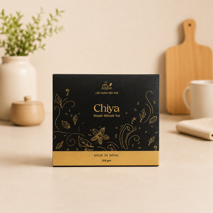 A box of Chiya (Nepalese Tea) by the brand ALIVE, displayed on a light beige countertop with a blurred background showing a mug, cutting board, and potted plant.